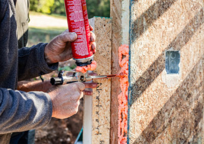 Crew member applying spray foam to SIP panel seam.