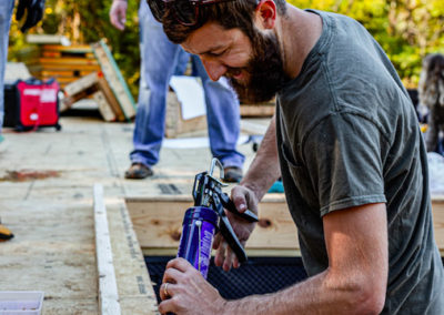 Builder applying caulk sealant between subfloor and bottom plate.