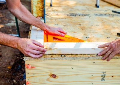 Builders using speed square at the corner of a bottom plate.